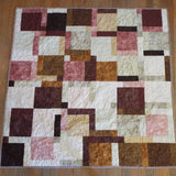 Flat lay of handmade quilt done in shades of brown, rose, and cream