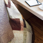 Handmade rose-gold quilt shown draped over a chair at a desk