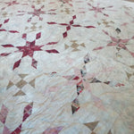 Angled lay of Scarlet Correspondence Queen Quilt showing more detail of design and stitching.