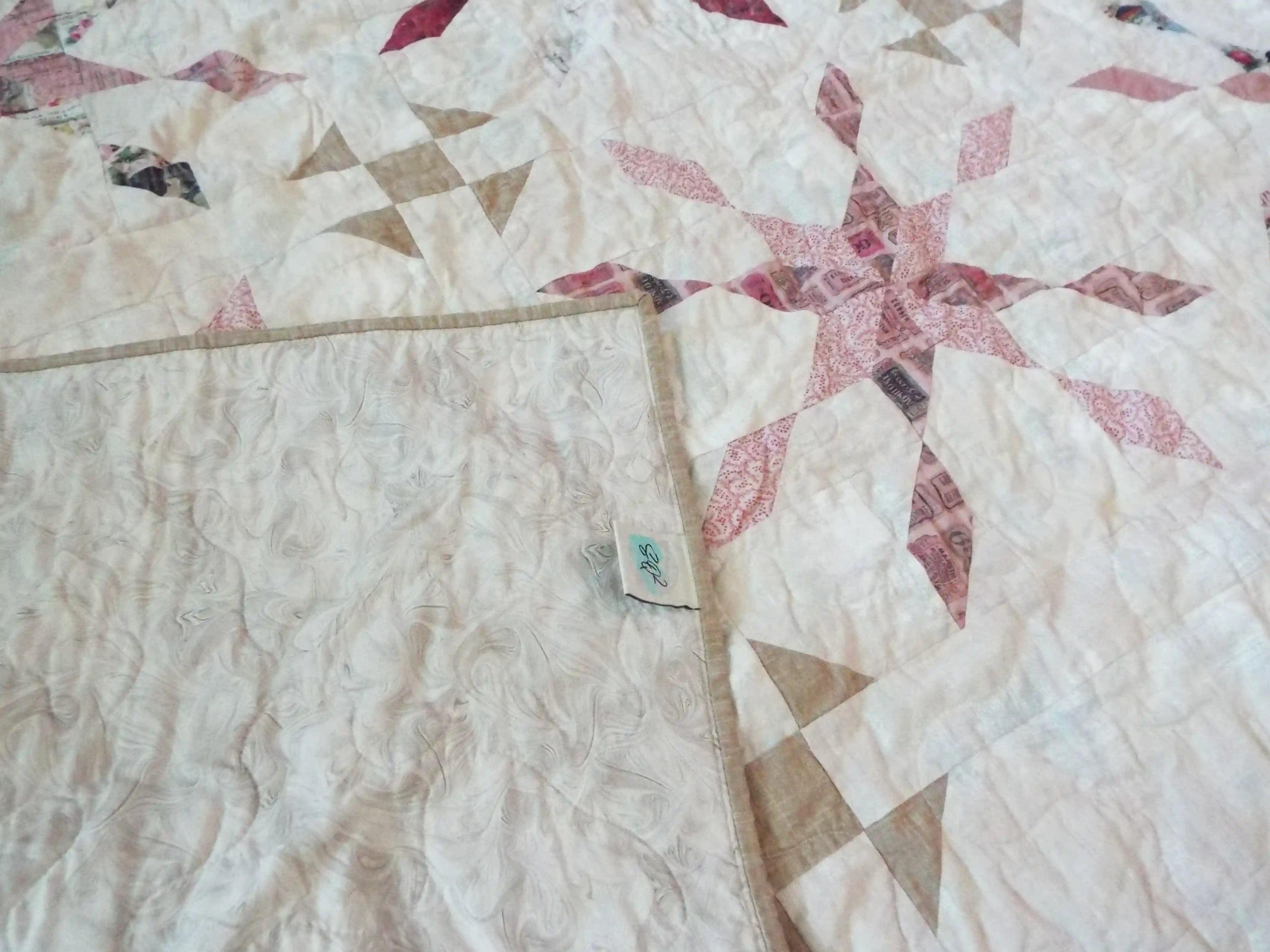 Corner flipped showing the backing of Scarlet Correspondence Queen Quilt.