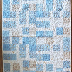 Full flat lay of handmade baby quilt in soft blue, cream, and tan with bunny fabric prints