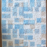 Full flat lay of handmade baby quilt in soft blue, cream, and tan with bunny fabric prints