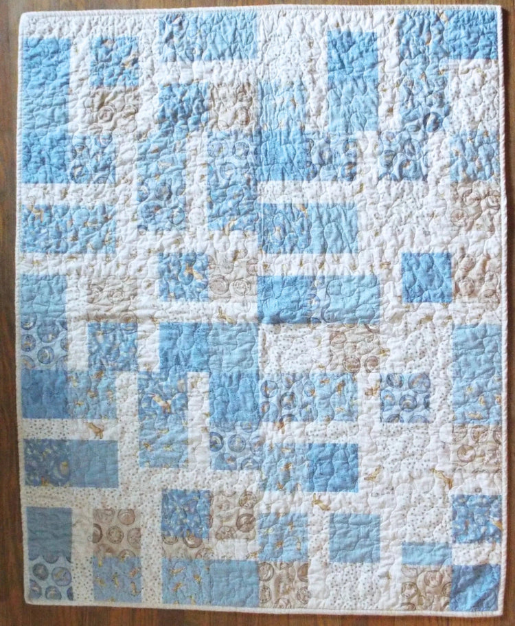 Full flat lay of handmade baby quilt in soft blue, cream, and tan with bunny fabric prints