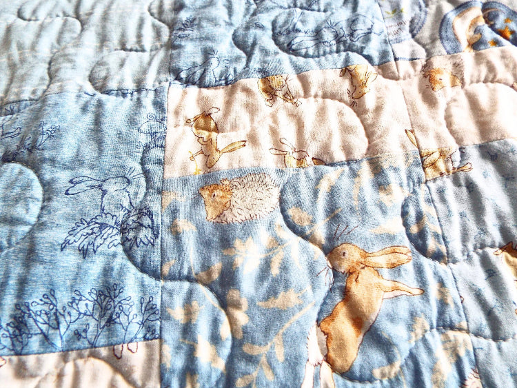 Close-up of bunny fabric and free-motion quilting on handmade blue baby quilt