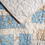 Close-up of handmade blue baby quilt with bunny print and white tone-on-tone backing