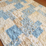 Angled lay of quilt showing stitching detail and close up of fabrics