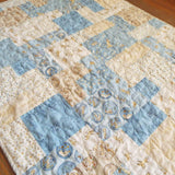 Angled lay of quilt showing stitching detail and close up of fabrics