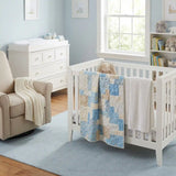 Quilt shown draped over a crib in a blue nursery