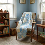 Quilt shown draped over a reading chair in the corner of a blue room