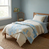 Quilt shown laid over a child's bed in a blue bedroom