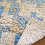 Quilt shown with corner flipped up to show the backing and stitching detail