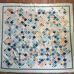 Softspoken Summer King Quilt flat lay showing entire quilt on a wooden floor.