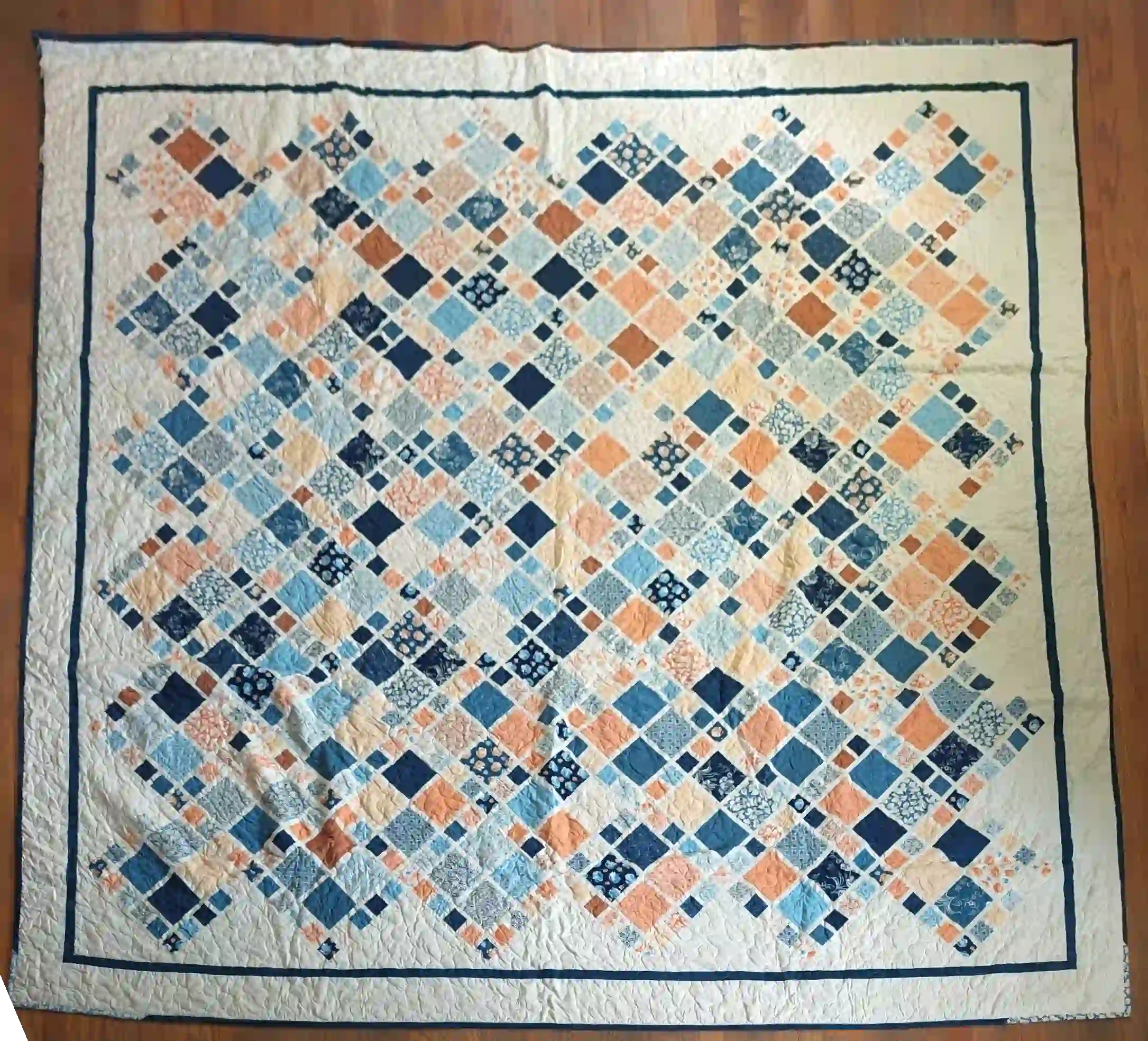 Softspoken Summer King Quilt flat lay showing entire quilt on a wooden floor.