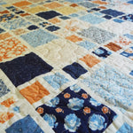 Close mid-range view showing intricate patchwork blocks and gentle quilting texture across the fabric.