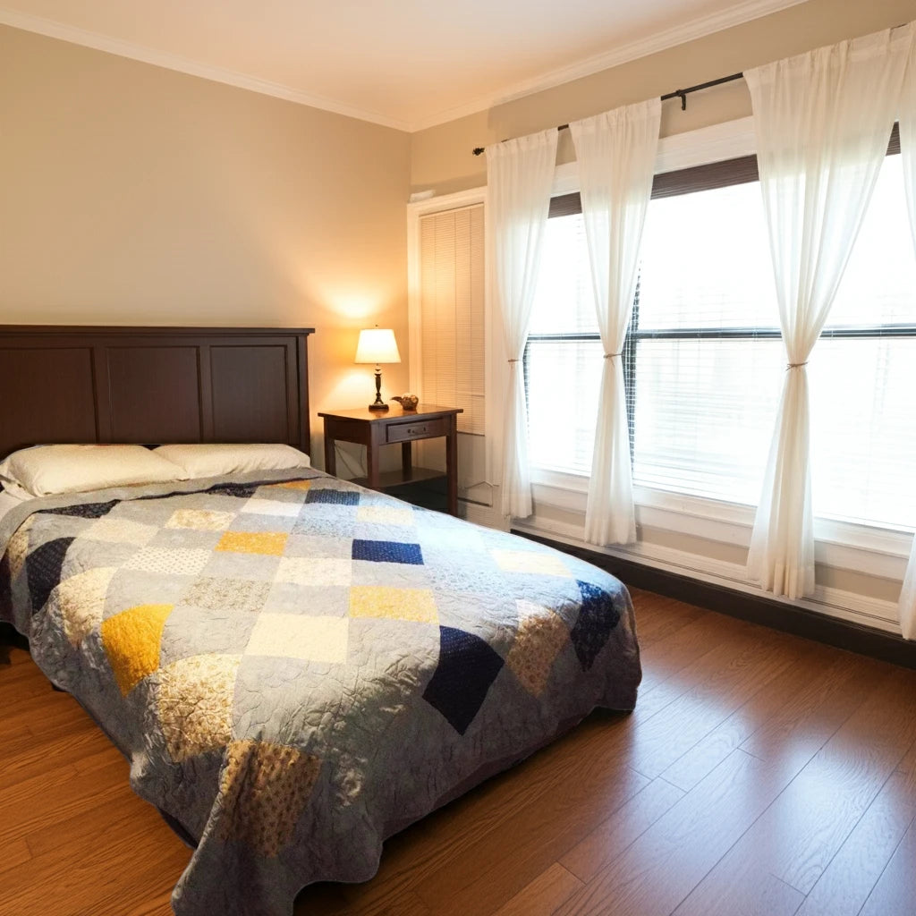 Queen patchwork quilt on bed with large windows and natural light, handmade in blue and gold Somerset Blues fabric.
