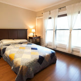 Queen patchwork quilt on bed with large windows and natural light, handmade in blue and gold Somerset Blues fabric.