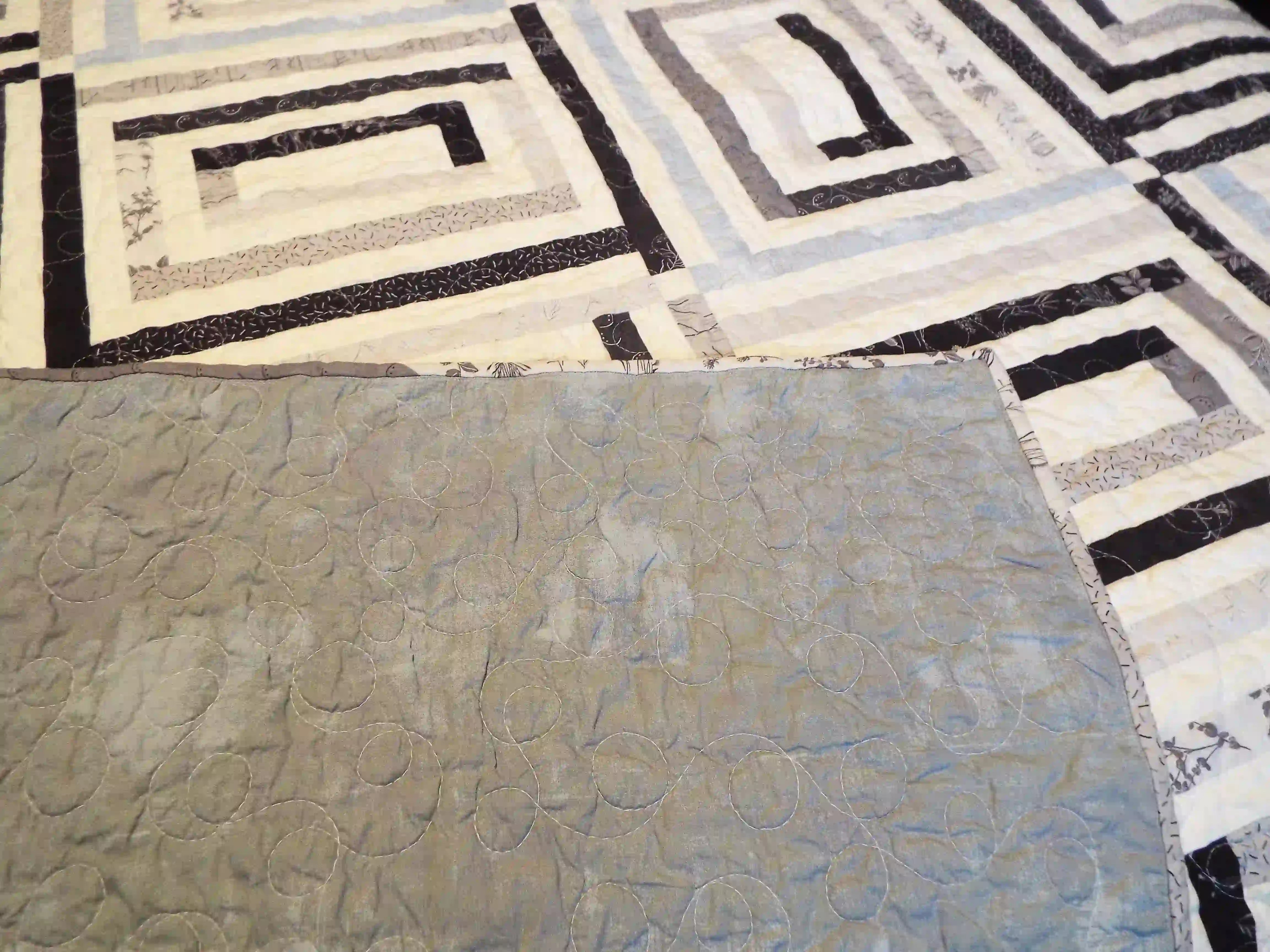 Quilt with corner flipped up to show backing as well as top and quilting stitches