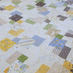Handmade twin quilt close up of floral, geometric, and gingham fabrics that make up the quilt top