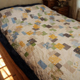 Angled view of twin/full handmade quilt with soft cotton texture and spring colors