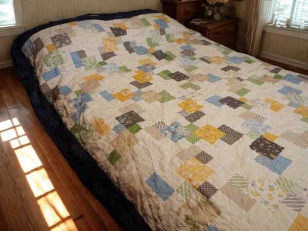 Angled view of twin/full handmade quilt with soft cotton texture and spring colors