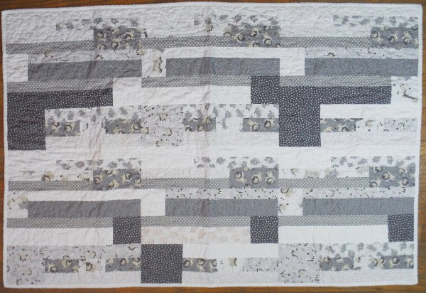 Flat lay of Starlit Trails gray baby quilt