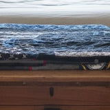 Sailor tribute quilt shown folded on a wooden trunk.