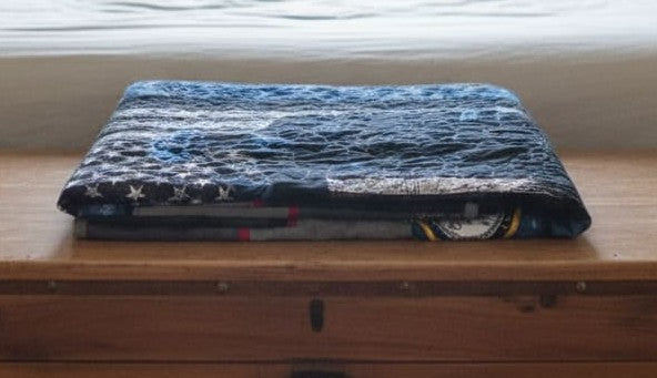 Sailor tribute quilt shown folded on a wooden trunk.