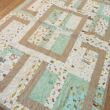 Angled lay of Stories in the Woods Baby Quilt showing closer detail of quilt.