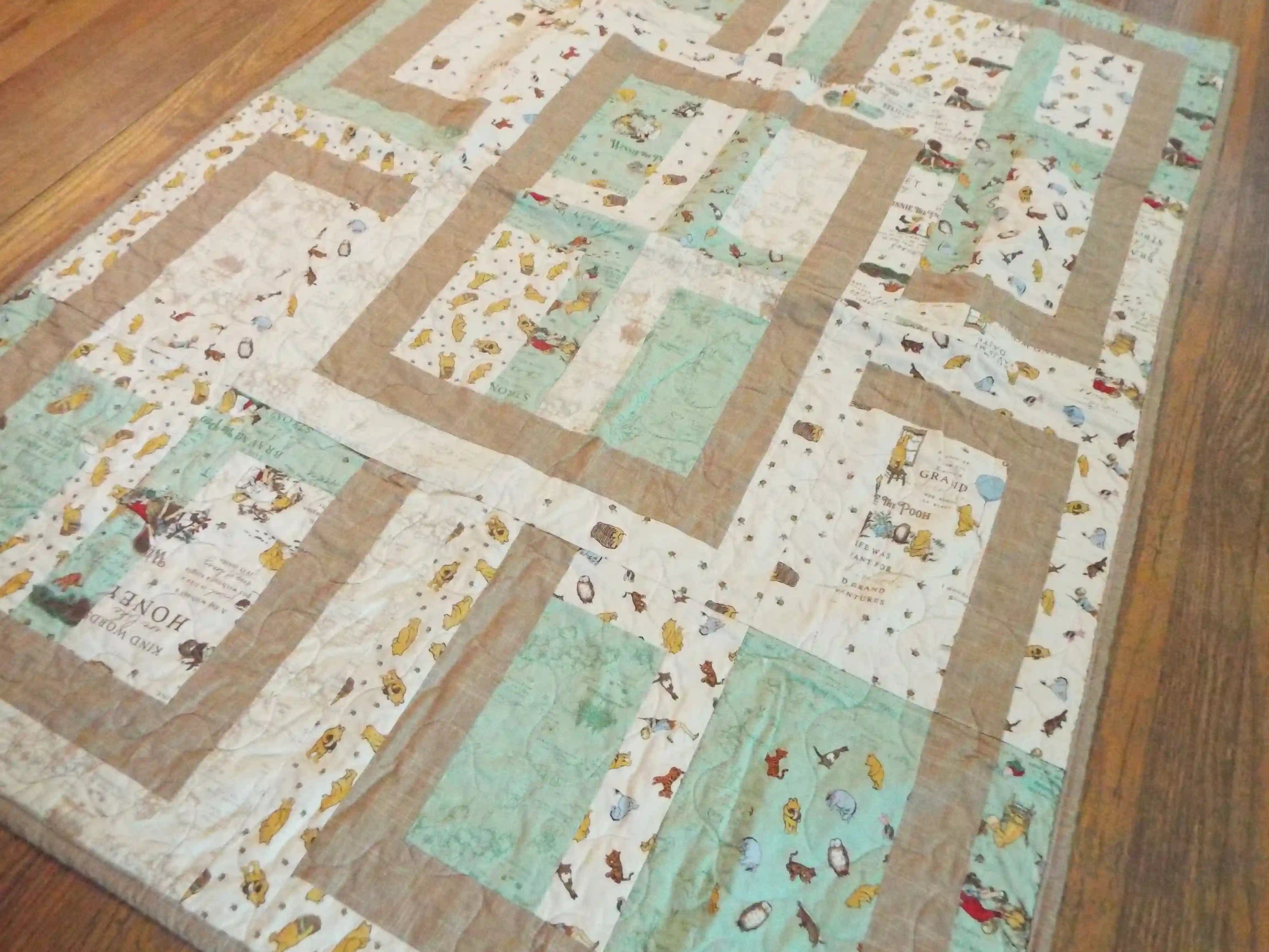 Angled lay of Stories in the Woods Baby Quilt showing closer detail of quilt.