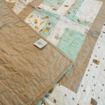 Corner flipped up on Stories in the Woods Baby Quilt showing backing detail.