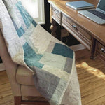 Handmade teal and cream throw shown over a chair at a desk by a window