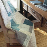 Handmade teal and cream throw shown over a chair at a desk by a window