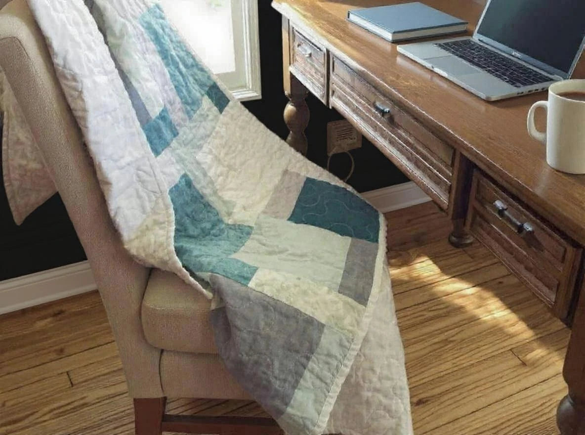 Handmade teal and cream throw shown over a chair at a desk by a window
