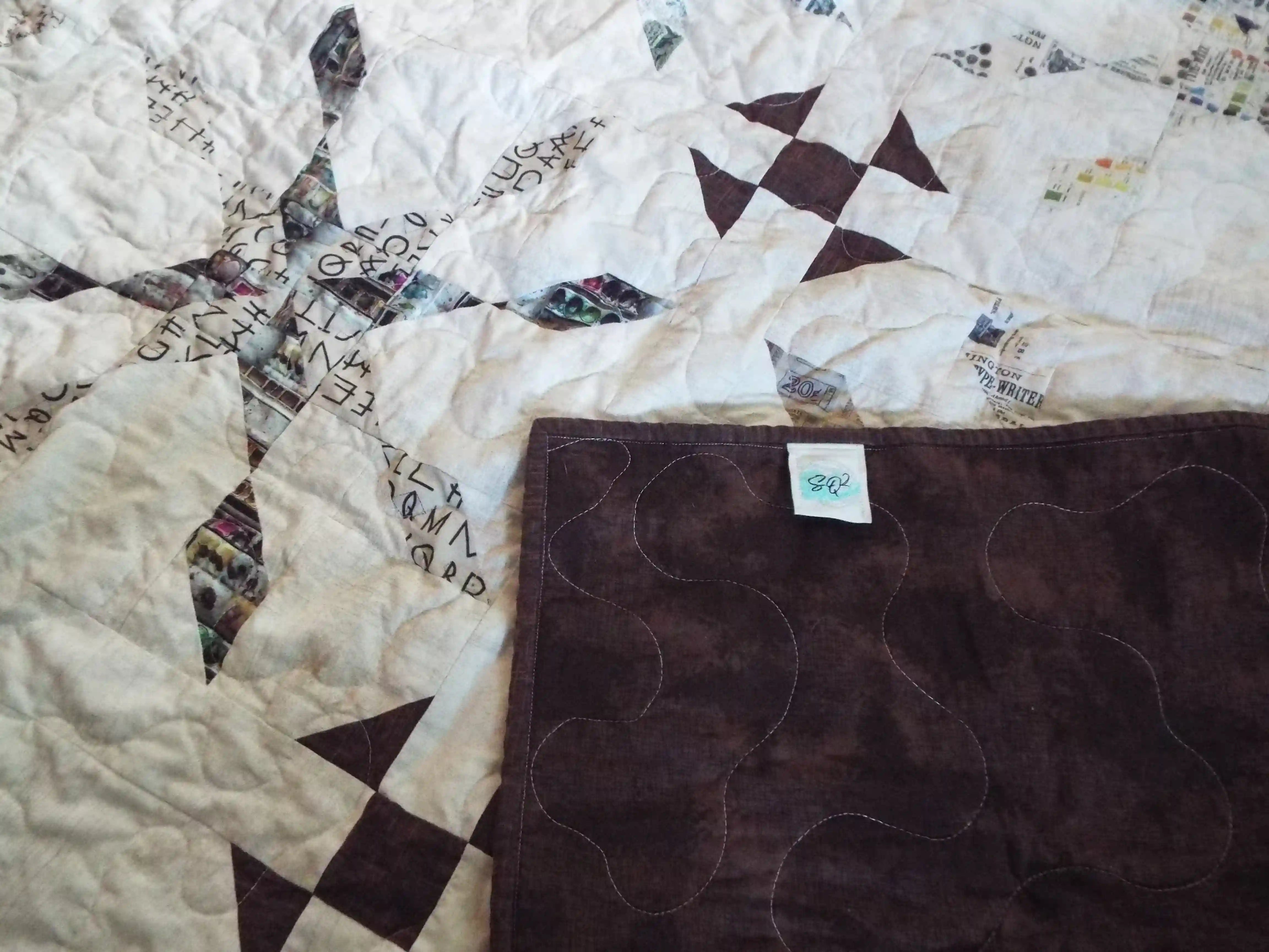 The Archivist Queen Quilt shown with the corner flipped over to show the backing.