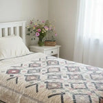 Twin floral handmade quilt shown in minimalist bedroom with soft lighting