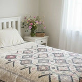 Twin floral handmade quilt shown in minimalist bedroom with soft lighting