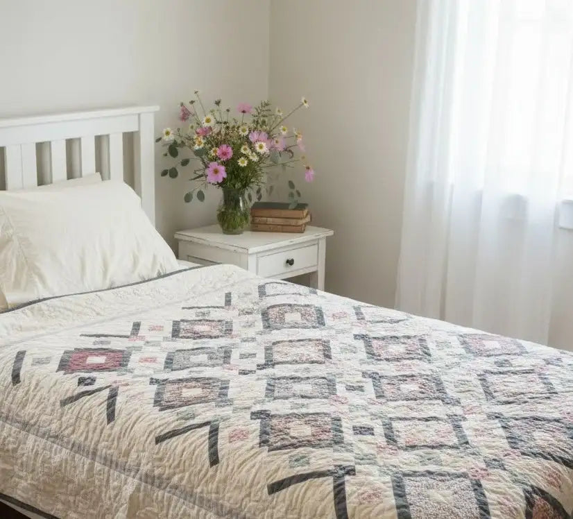 Twin floral handmade quilt shown in minimalist bedroom with soft lighting