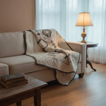 Twin Floral Handmade Quilt shown draped over a sofa in a minimally decorated living room with soft lighting.