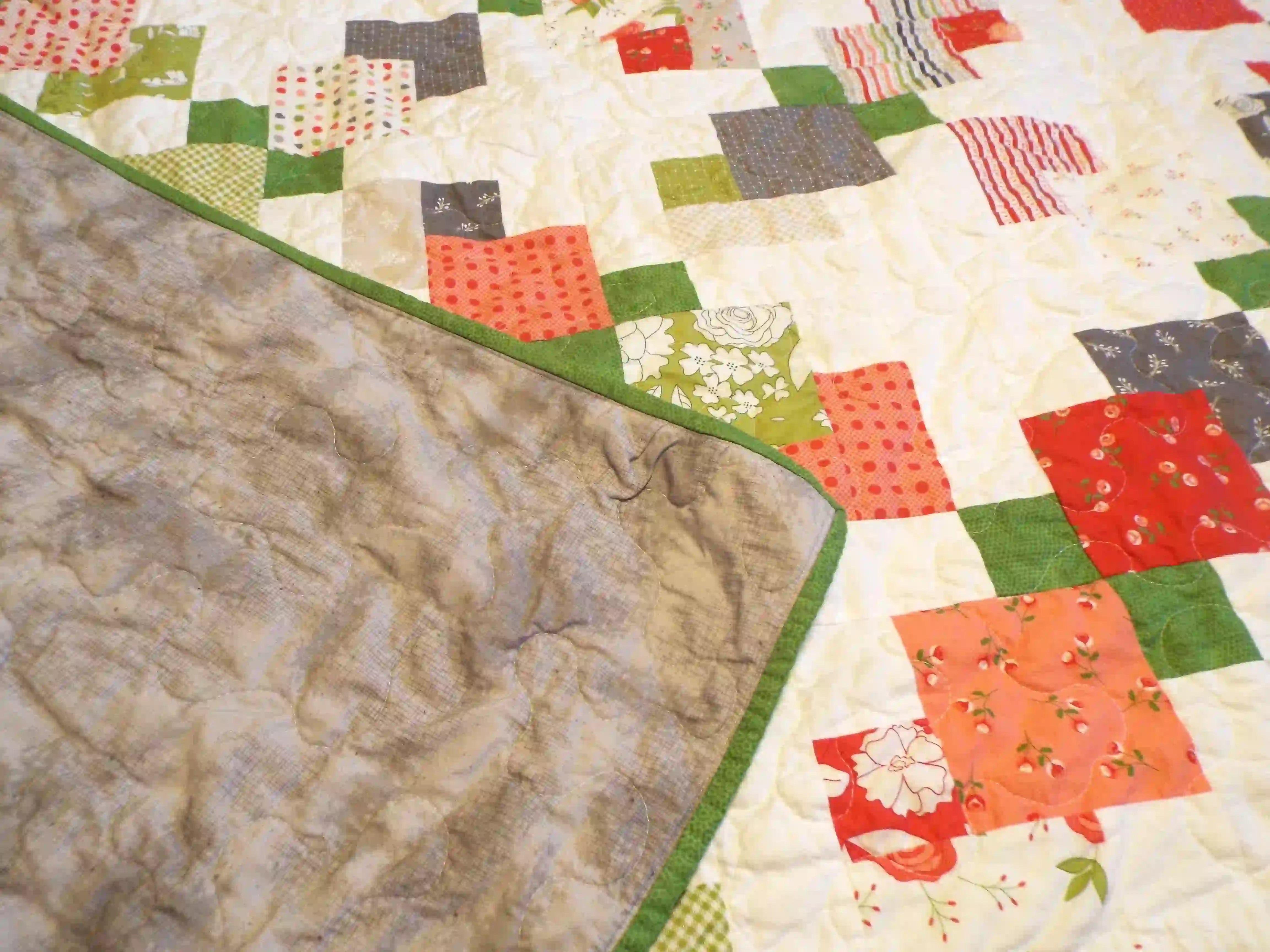Corner flipped up to show the backing of quilt.