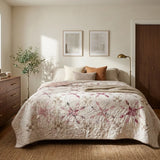 Scarlet Correspondence Queen Quilt is styled on a bed in a warm, modern bedroom. The room features a dark wood dresser, a floor lamp, a window with natural light, and neutral-toned walls.