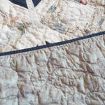 Detail shot showing backing, binding, and quilt top along with stitching