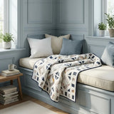 Handmade lap quilt shown on a window seat in a light blue room