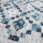 Angled lay of Weathered Blue lap quilt showing close up of fabrics within quilt.