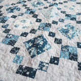 Angled lay of Weathered Blue lap quilt showing close up of fabrics within quilt.