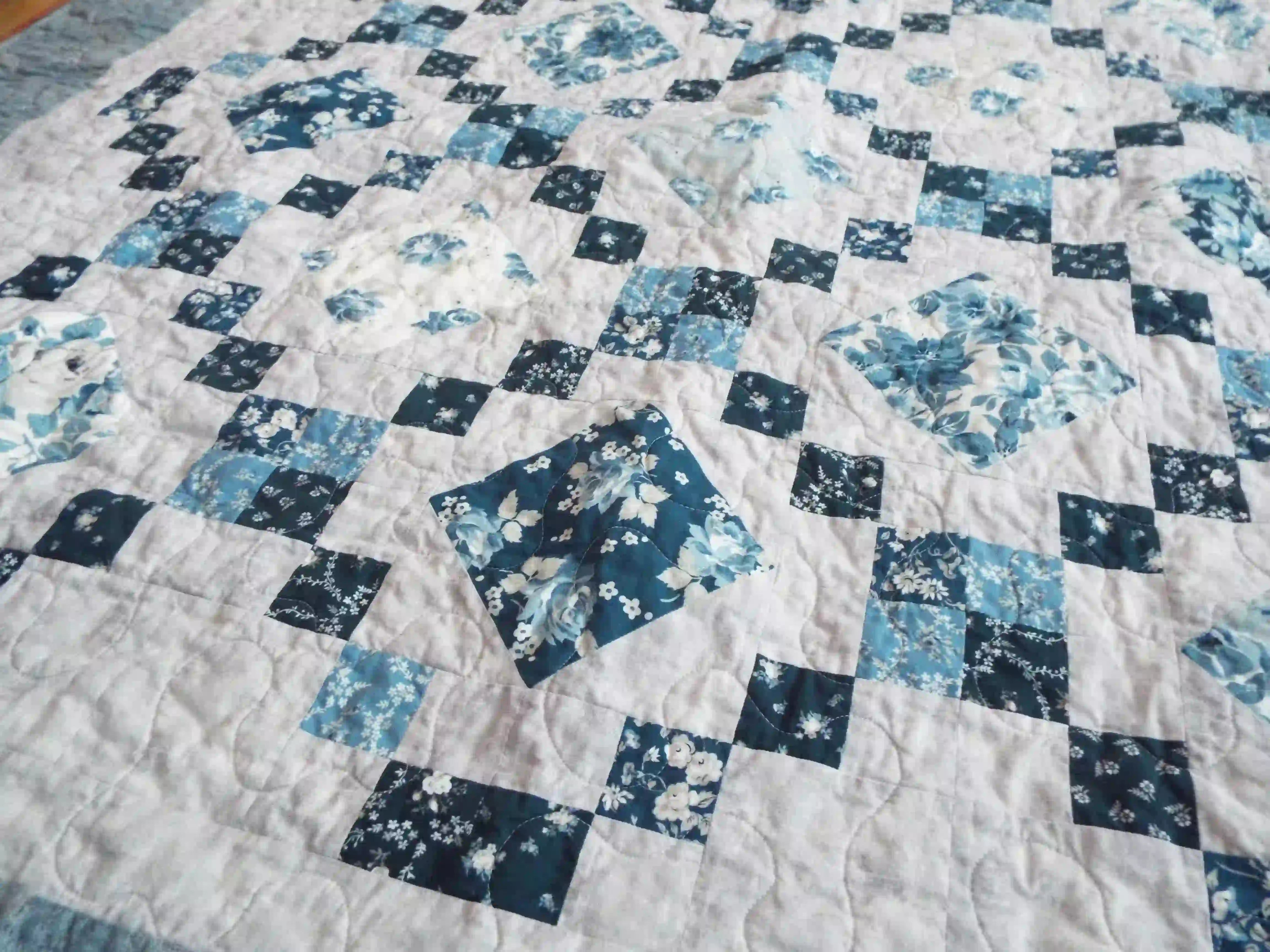 Angled lay of Weathered Blue lap quilt showing close up of fabrics within quilt.