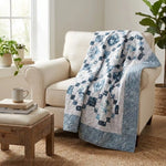 Weathered Blue lap quilt draped over a beige armchair in a cozy living room.