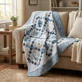 The Weathered Blue lap quilt draped over a beige sofa in a cozy living room.