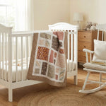 Handmade quilt draped over the side of a white crib in a minimal nursery.