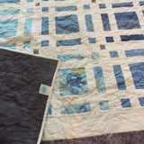 Woven Breeze Queen shown with the corner flipped up to see the backing, quilt stitching, and quilt top detail.