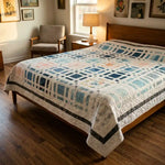 Woven Breeze queen quilt shown in a curated modern bedroom with wooden floors.